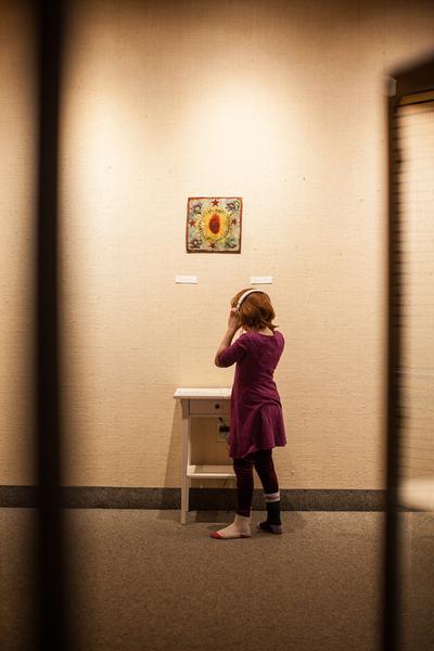 A girl wearing headphones listens to an audio exhibit in an art gallery