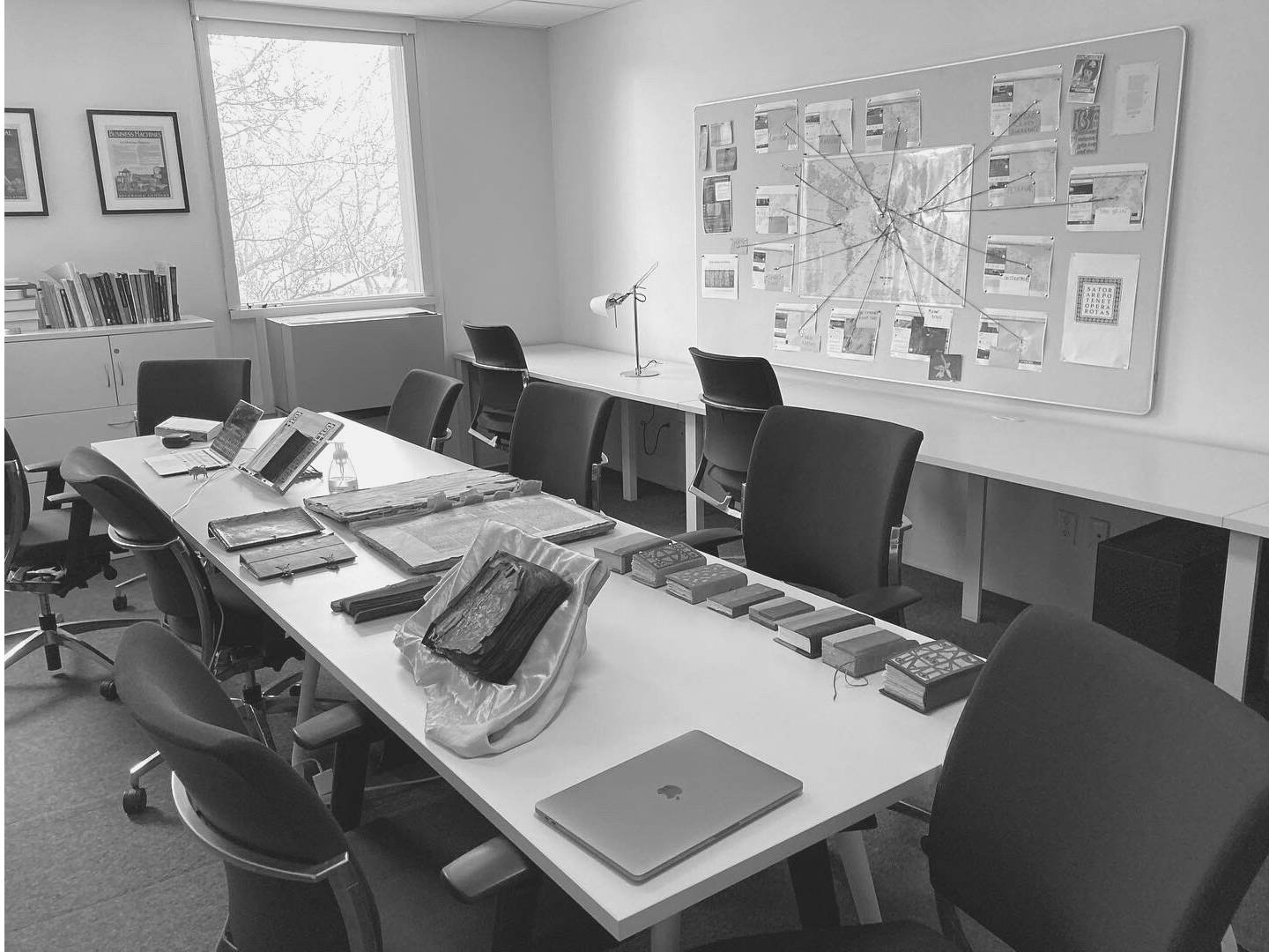 JHI space features a large table in the centre of the room with materials displayed on it. Black and white photo.