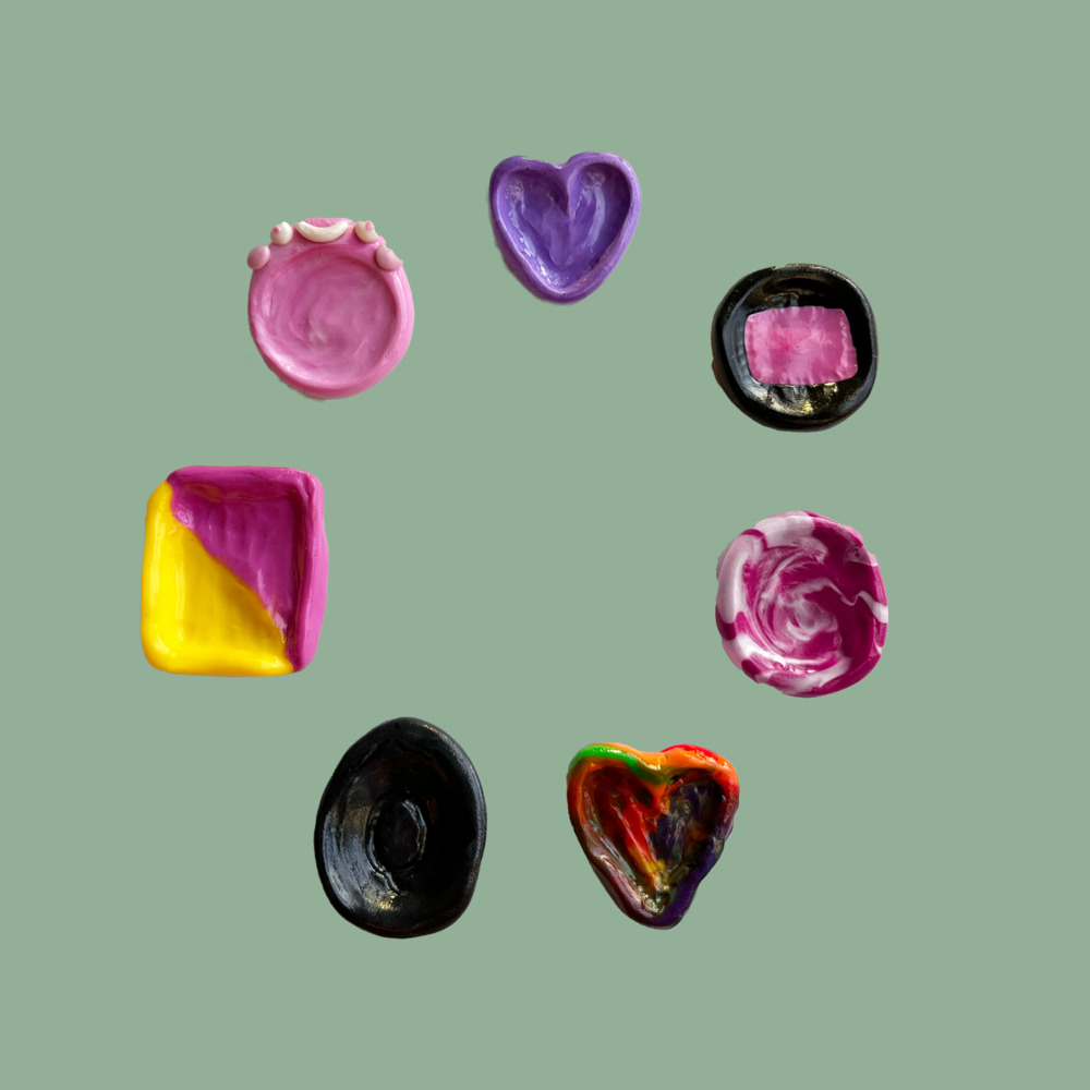seven worry stones. clockwise starting from the top:

1) heart-shaped, lavender

2) circular, black with a pink rectangle in the centre

3) circular, magenta and white swrils in circles

4) heart-shaped, rainbow swirls streaks but heavily muddled 

5) circular, black, has a q carved in its centre

6) rectangular, pink and yellow diagonal halves

7) circular, light pink, has a smiley face with a blush